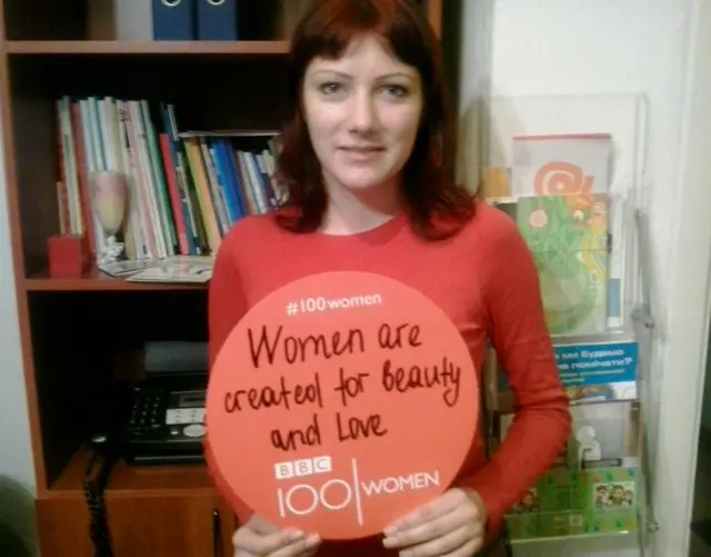 A woman holding a sign saying 'Women are created for beauty and love'