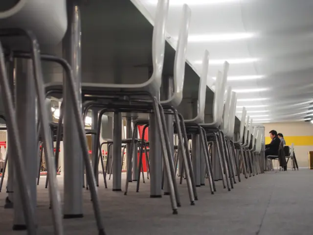 empty chairs and a few journalists at a long row of desks