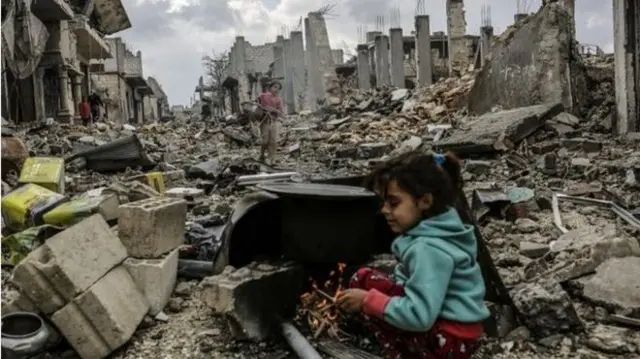 A child sits on rubble in Syria