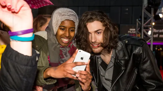 Hozier poses with a fan on the red carpet