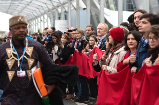 Protesters lining up with a long strip of red fabric