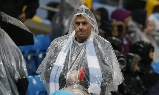 A Manchester City fan wears a waterproof poncho