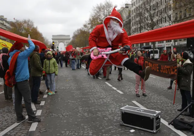 Protester leaps in the air with a guitar, dressed as Santa Claus