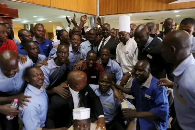 Hotel workers pose for a picture with Radisson Blu hotel owner Kome Cesse after the Radisson reopened in Bamako