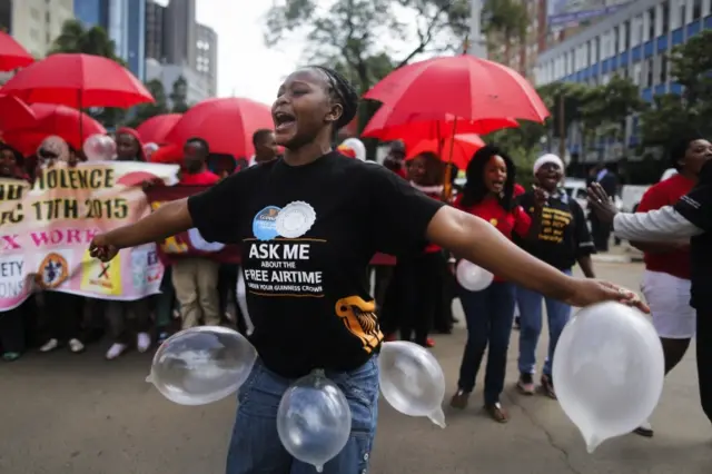 A Kenyan female sex worker plays with inflated condoms as she walks with supporters and members of the lesbian, gay, bisexual and transgender (LGBT) community in Nairobi, Kenya