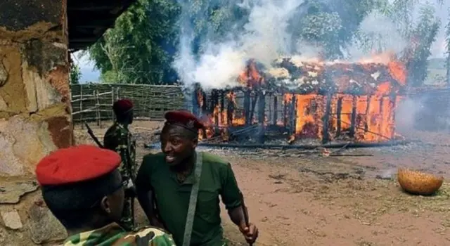 Soldiers in Burundi with a building on fire behind them