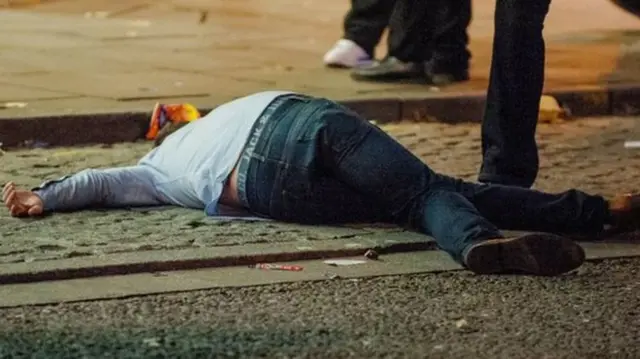 Drunk man lying in a street