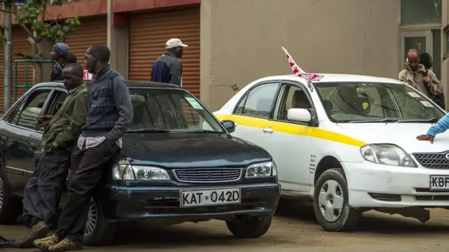 Men wait by taxis in Kenya