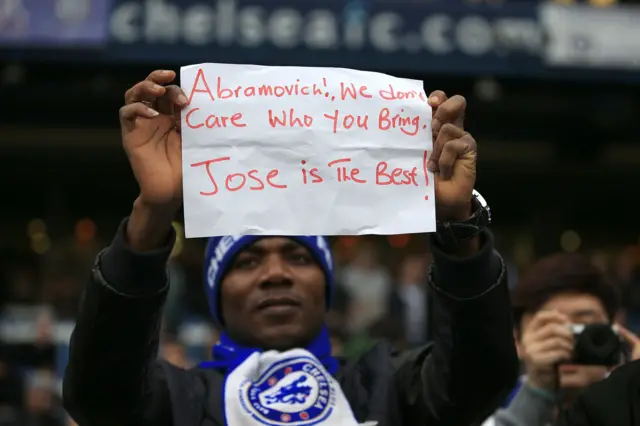 A Chelsea fan holds up a sign supporting Jose Mourinho