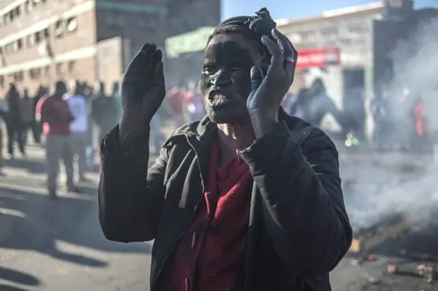 A women covered in soot gestures and shouts towards foreign nationals outside the Jeppies Hostles, in the Jeppestown area of Johannesburg, on April 17, 2015 after residents from the Jeppie Hostles, purportedly torched a passing vehicle in the early hours.