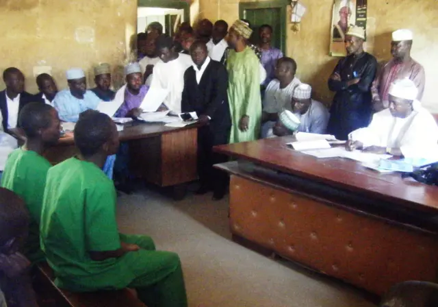 A picture taken on January 22, 2014 shows two suspected homosexuals in green prison uniforms (L) sitting before Judge El-Yakubu Aliyu during court proceedings at Unguwar Jaki Upper Sharia Court in the northern Nigerian city of Bauchi.