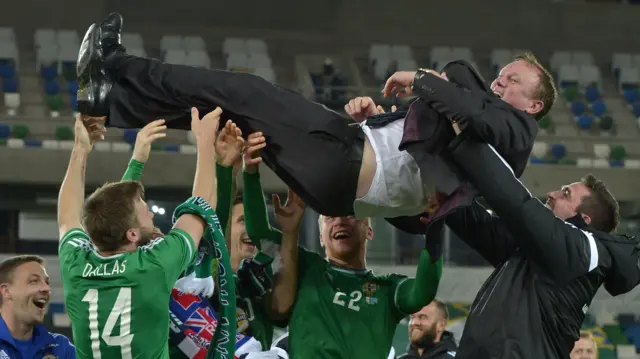 Michael O'Neill is thrown in the air by Northern Ireland players