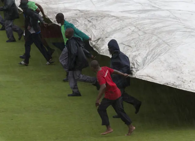 Ground staff cover the playing surface as play is suspended