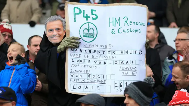 A fan dressed as Jose Mourinho mask holds a P45 in the stand