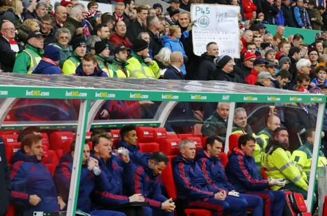 Louis Van Gaal looks on as behind a Stoke fan wearing a Jose Mourinho