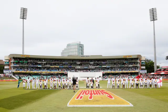 The teams stand for the national anthem