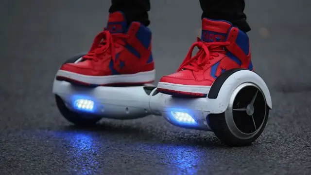 A person poses as he rides a hoverboard