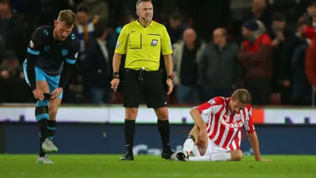 Peter Crouch of Stoke City sits on the ground before going off