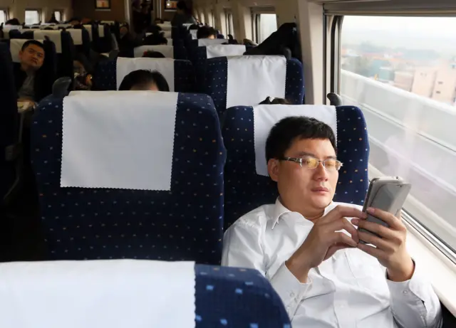 A man looks at his phone on a train