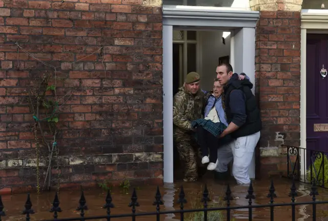 A woman being rescued from her flooded home