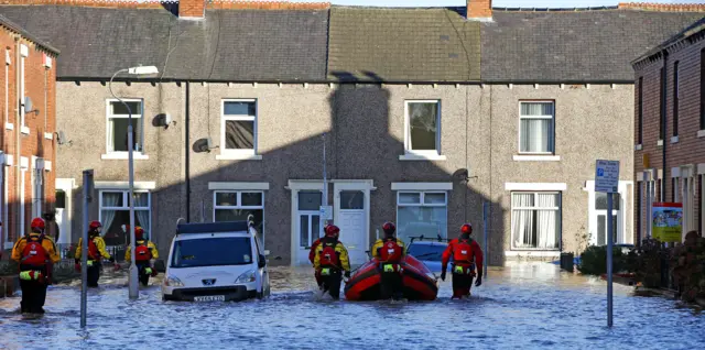 Rescuers walking along flooded streets in Carlisle