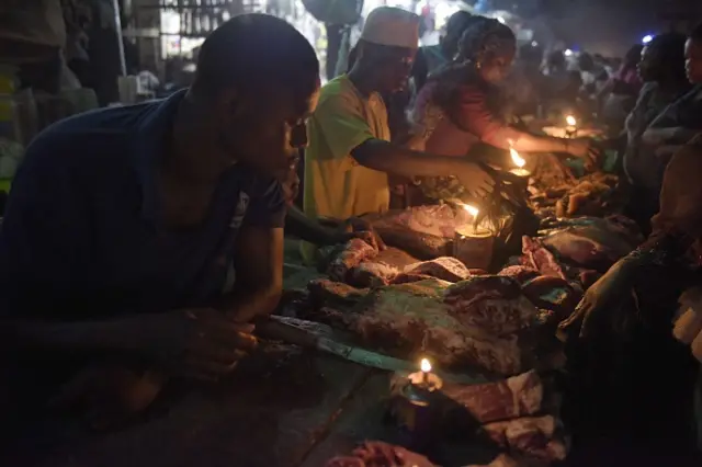 Vendors sell meat at the Oshodi night market in Lagos, late on June 6, 2015, lighting their stall with a fuel lamp in absence of electricity