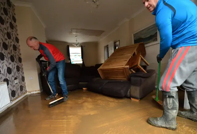 Men cleaning up flooded house in Cockermouth