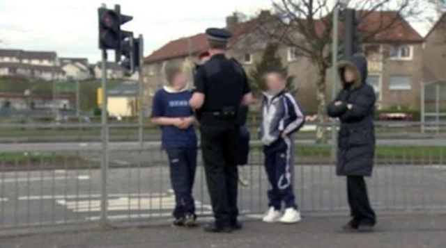 Police officer talking to 3 young people in the street