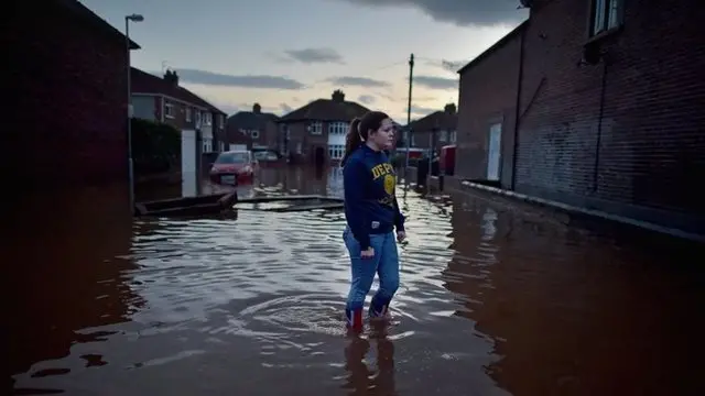 A girl stands in a flooded street