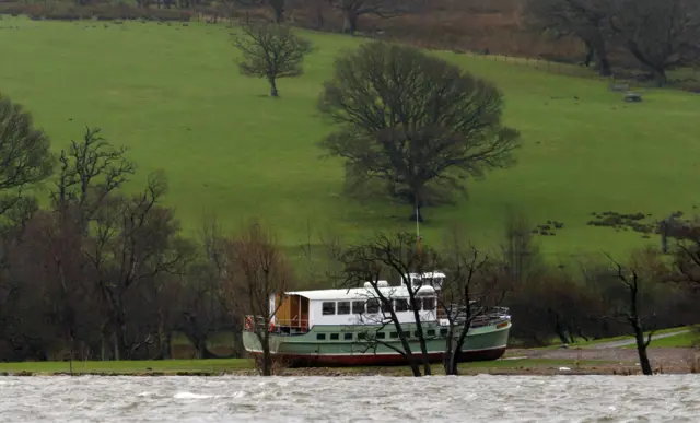 A large boat appears to be washed up in a field around