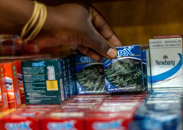 A customer pulls a pack of condoms from a rack in a pharmacy in the Zimbabwean capital Harare on May 26, 2015