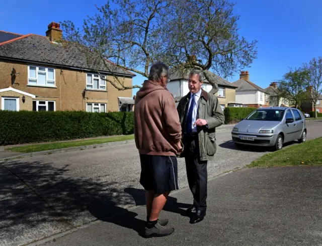 Ukip Leader Nigel Farage talks to a local man during canvassing in Sandwich, Kent