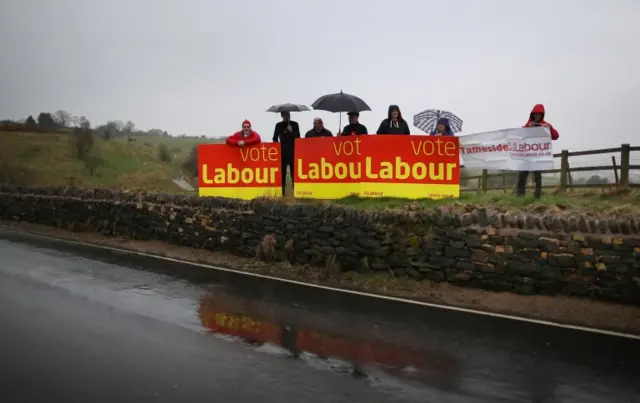 Labour party activists stand near to a Liberal Democrat party event in Hyde