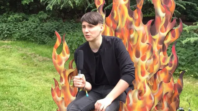 Dan Howell sits on a flame chair.