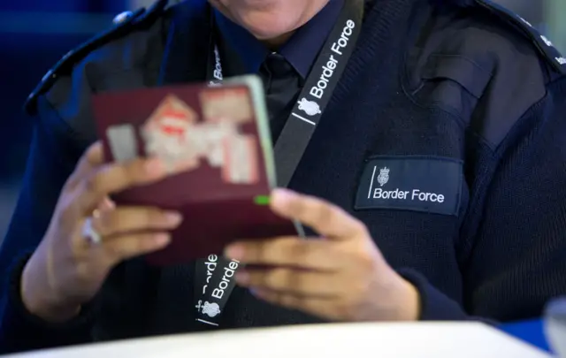 Border Force official checking a passport