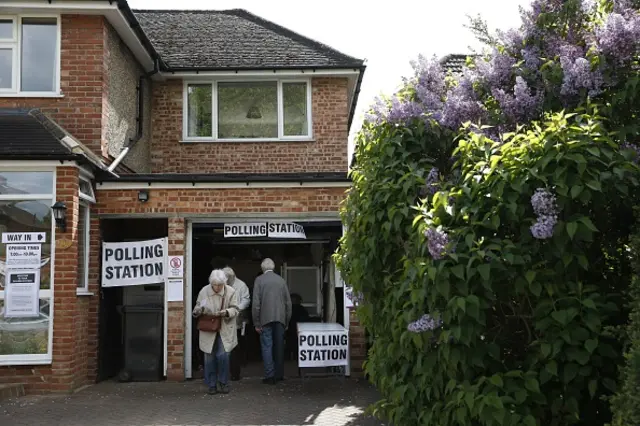 :Members of the public vote at a polling station set up in the garage of a house in Croydon