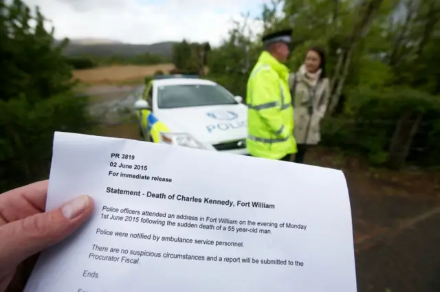 Printout of the police statement on the death of Charles Kennedy. A police officer is in the background.