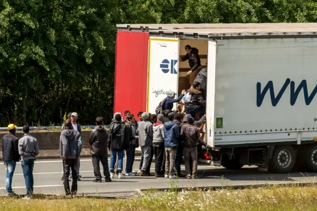 Migrants climb in the back of a lorry in Calais