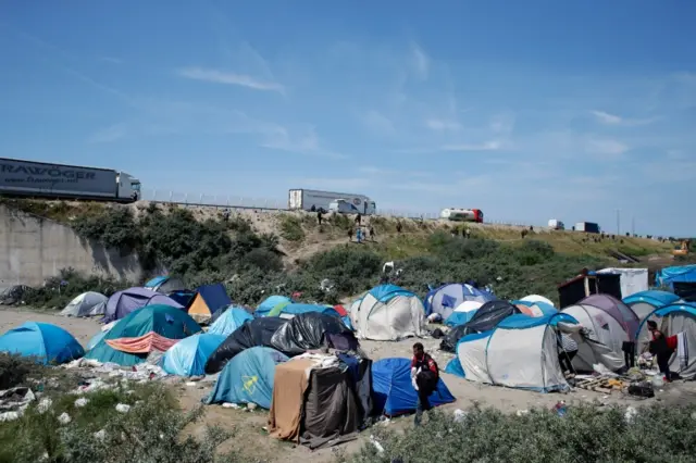 A migrant walks in a makeshift camp in Calais