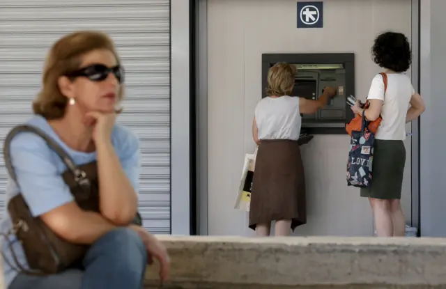 Women withdraw money from an ATM in Athens