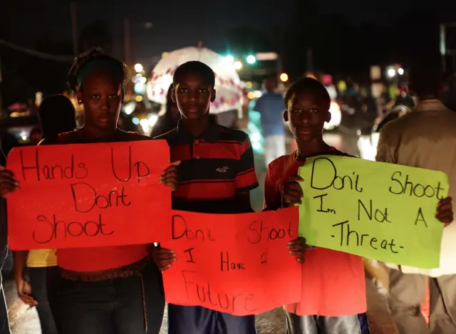 Demonstrators hold signs as they protest the shooting death of 18-year-old Michael Brown on August 15, 2014 in Ferguson, Missouri.