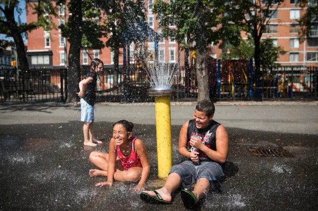 Jaeleen Ramirez (R), age 10, and Caesar Soto, age 10, cool off in a fountain on September 2, 2014 in New York City