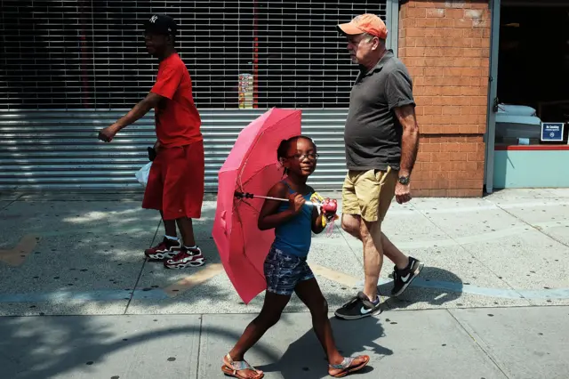 girl walks with a sun umbrella on a hot day in the East Village in Manhattan on June 11, 2015 in New York City.