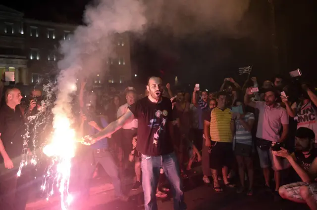 People light red flares while celebrating the "No" victory in the Greek referendum late in Athens on July 5, 2015.