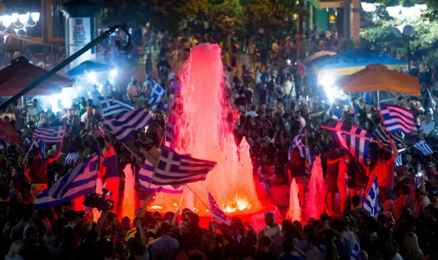 Supporters of the Syriza party and No vote campaign wave flags and react after results of the referendum in front of the Greek parliament in Athens on 5 July 2015