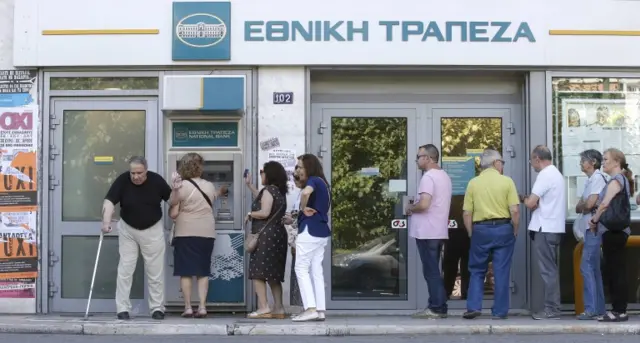 Referendum campaign posters that reads "No" in Greek are seen as people line up at an ATM outside a National Bank branch during a referendum vote in Athens, Greece, July 5, 2015