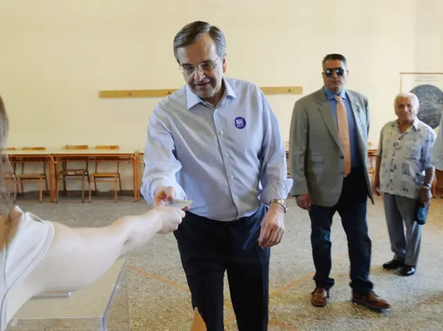 Former Greek Prime Minister and conservative opposition leader Antonis Samaras shows his ID as he prepares to vote at a polling station in the town of Pylos, southwestern Greece, Sunday, July 5, 2015