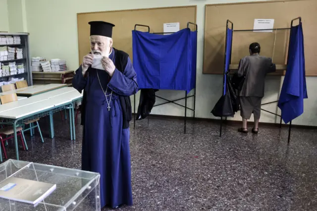 An Orthodox priest prepares to place a referendum vote in the ballot box at a school on July 5, 2015 in Athens, Greece