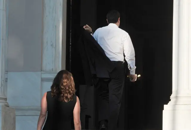 Greece"s Prime Minister Alexis Tsipras, right, arrives with his partner Peristera (Betty) Baziana at Maximos Mansion in Athens, Sunday, 5 July 2015