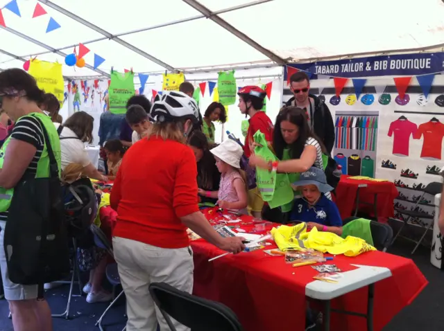 People and children sticking craft items on tabards